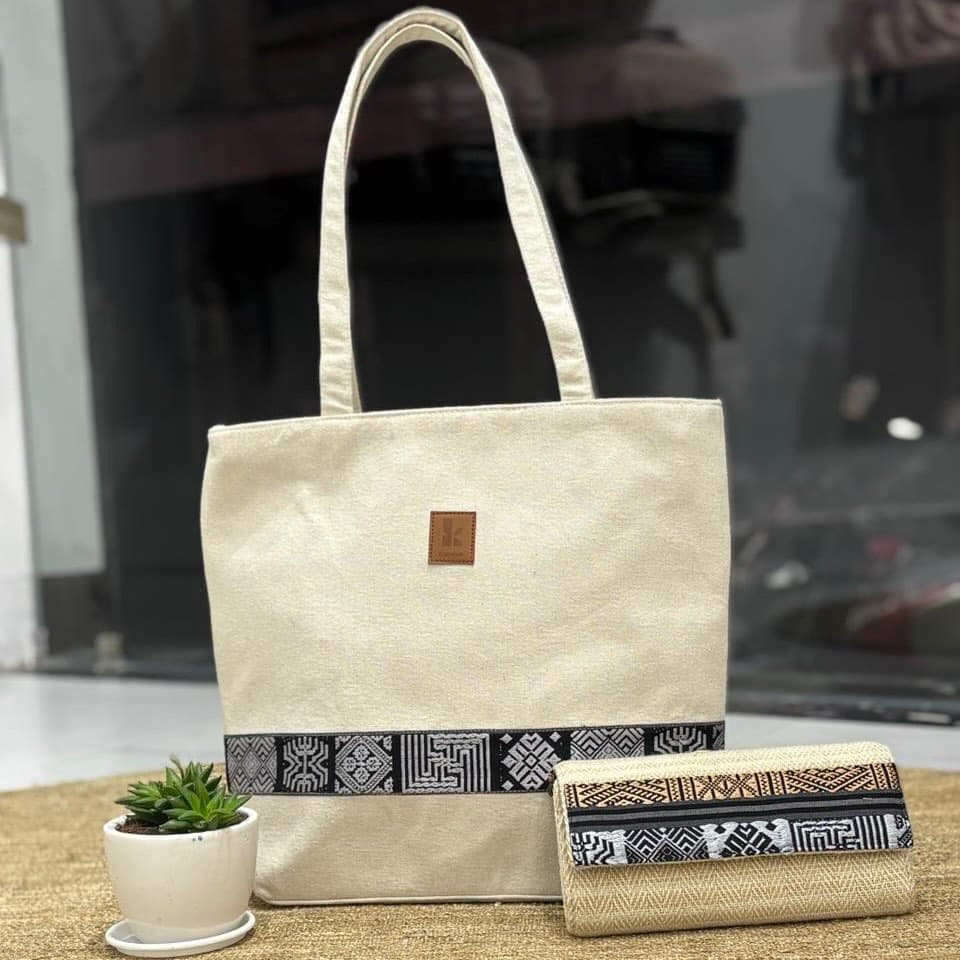 The Kanduk tote in Natural Canvas — a cream hemp tote with a woven band along its base, shown with the matching patterned clutch