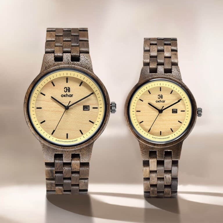Two walnut wristwatches with warm cream dials, standing side by side in raking sunlight
